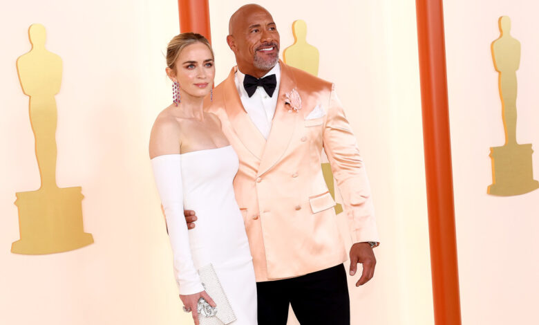 Emily Blunt looks stressed as 'The Rock' sits on her lap